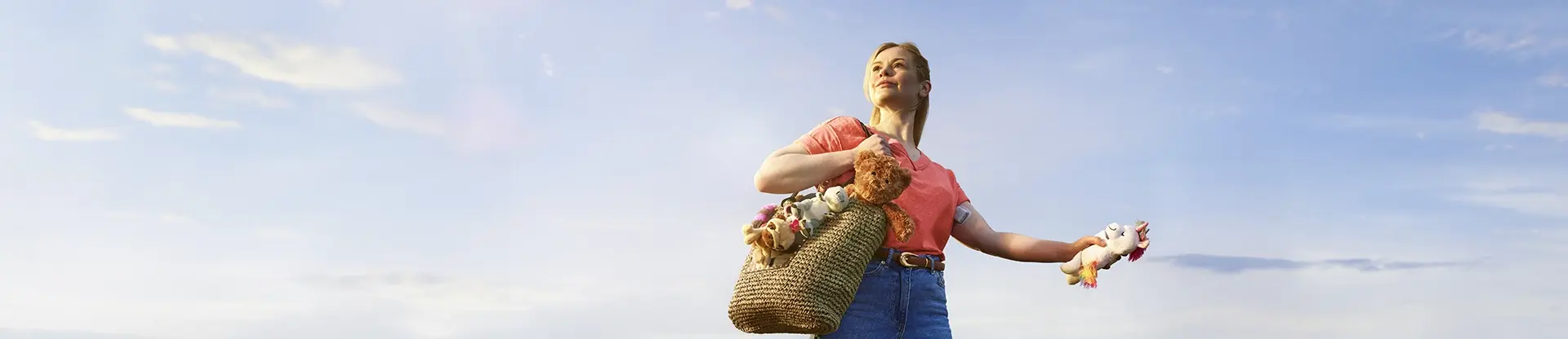 Woman standing outdoors holding a basket of toys and looking confidently ahead